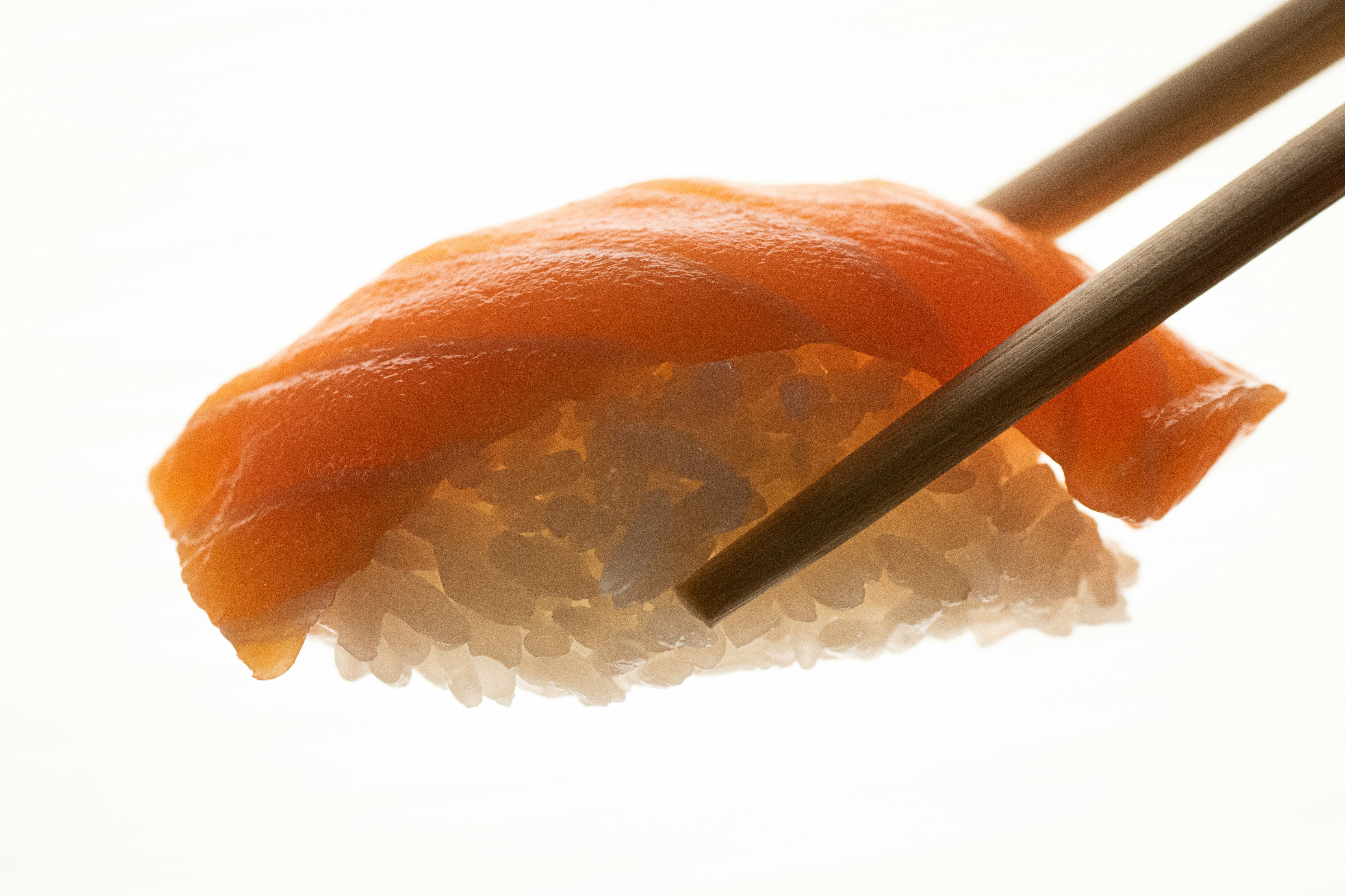 a close-up of Salmon Nigiri held by chopsticks
